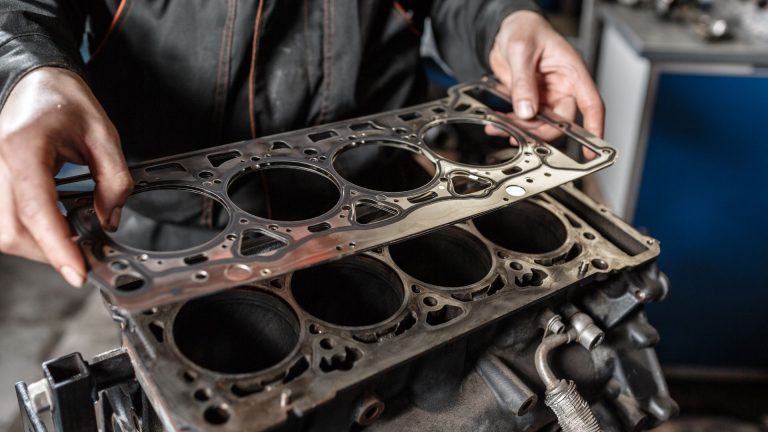 a man working on an engine block in a garage.