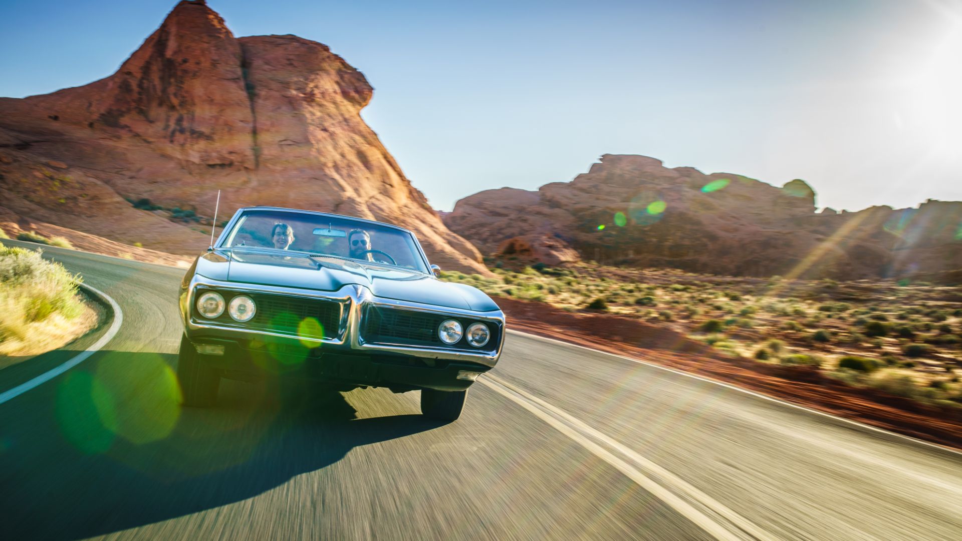 a car driving down a road in the desert.