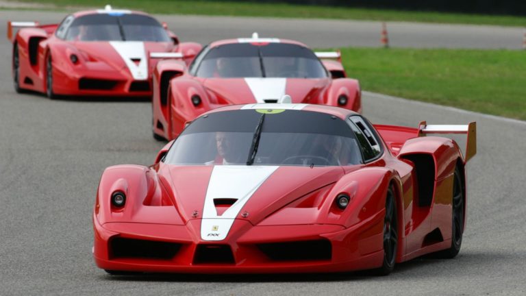 a group of red race cars driving down a race track.