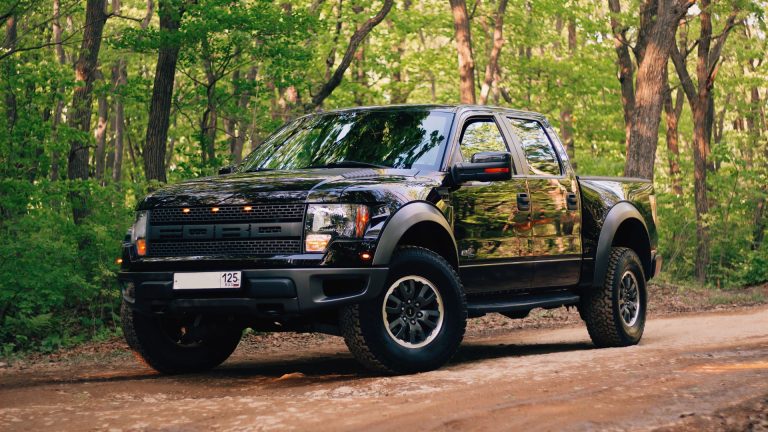 a black pickup truck driving down a dirt road.