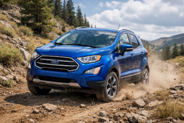 A blue Ford EcoSport SUV drives on a rocky dirt road in a mountainous, forested area under a partly cloudy sky.