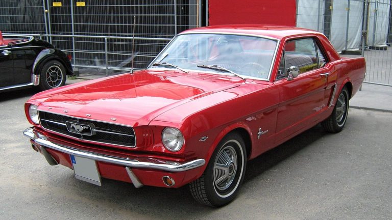 a red mustang parked next to a black mustang.