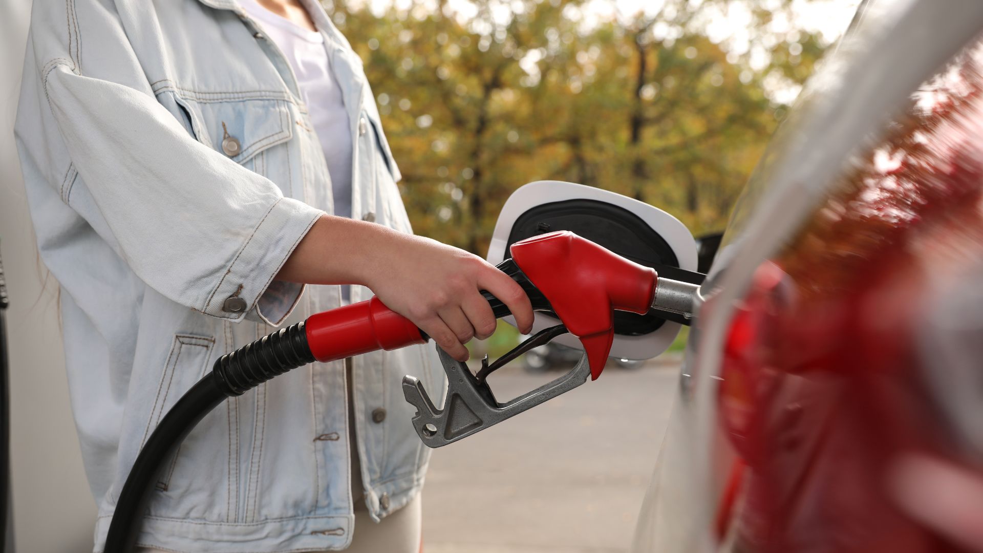 a woman pumping gas into her car at a gas station.