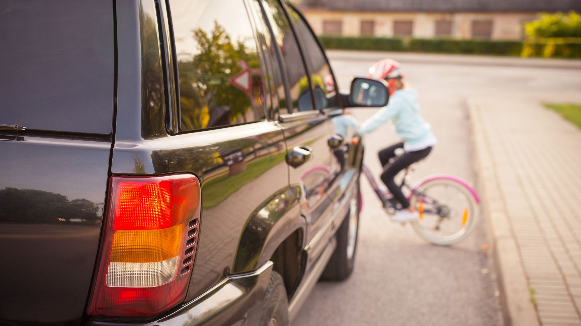 a man riding a bike next to a parked car.