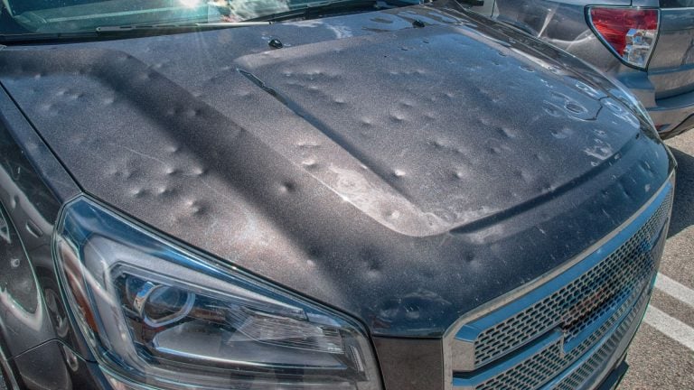 a close up of a car with a mattress on the hood.