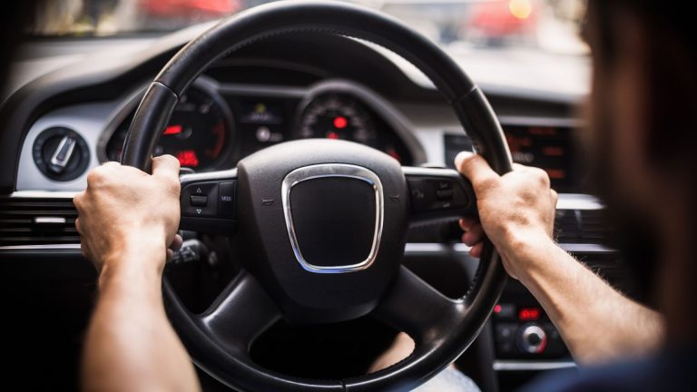 a man driving a car with a steering wheel.