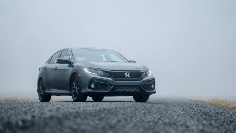 a gray car driving down a foggy road.