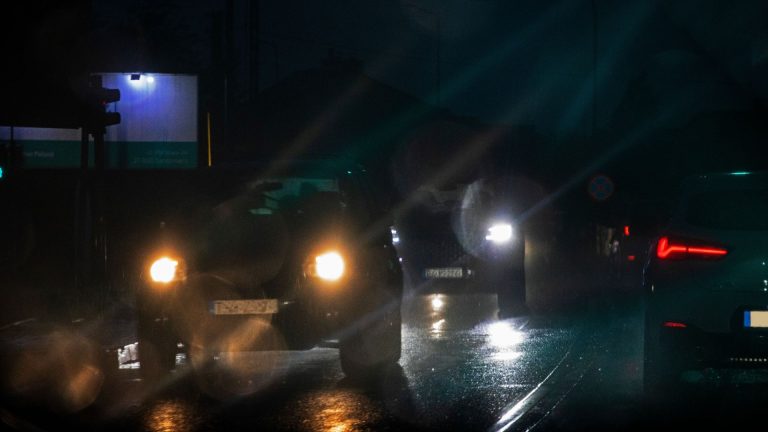 a couple of cars driving down a street at night.