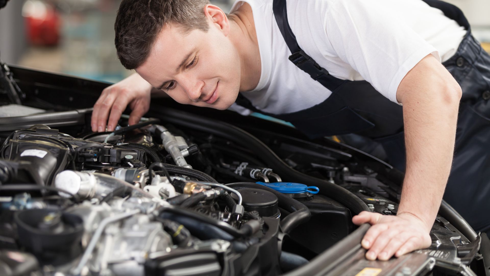 a man working on a car engine in a garage.