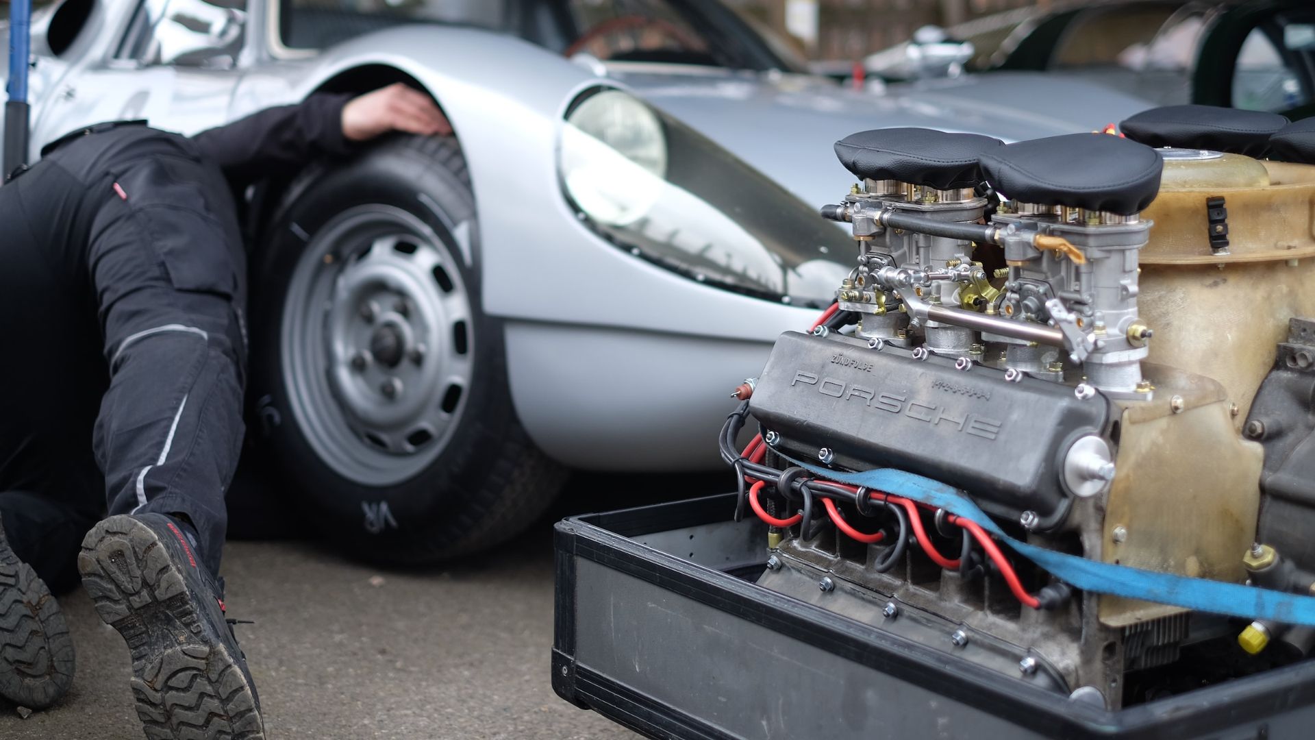 a man kneeling down next to a car engine.