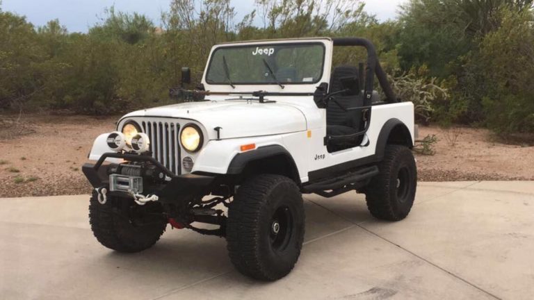 a white jeep is parked in a driveway.