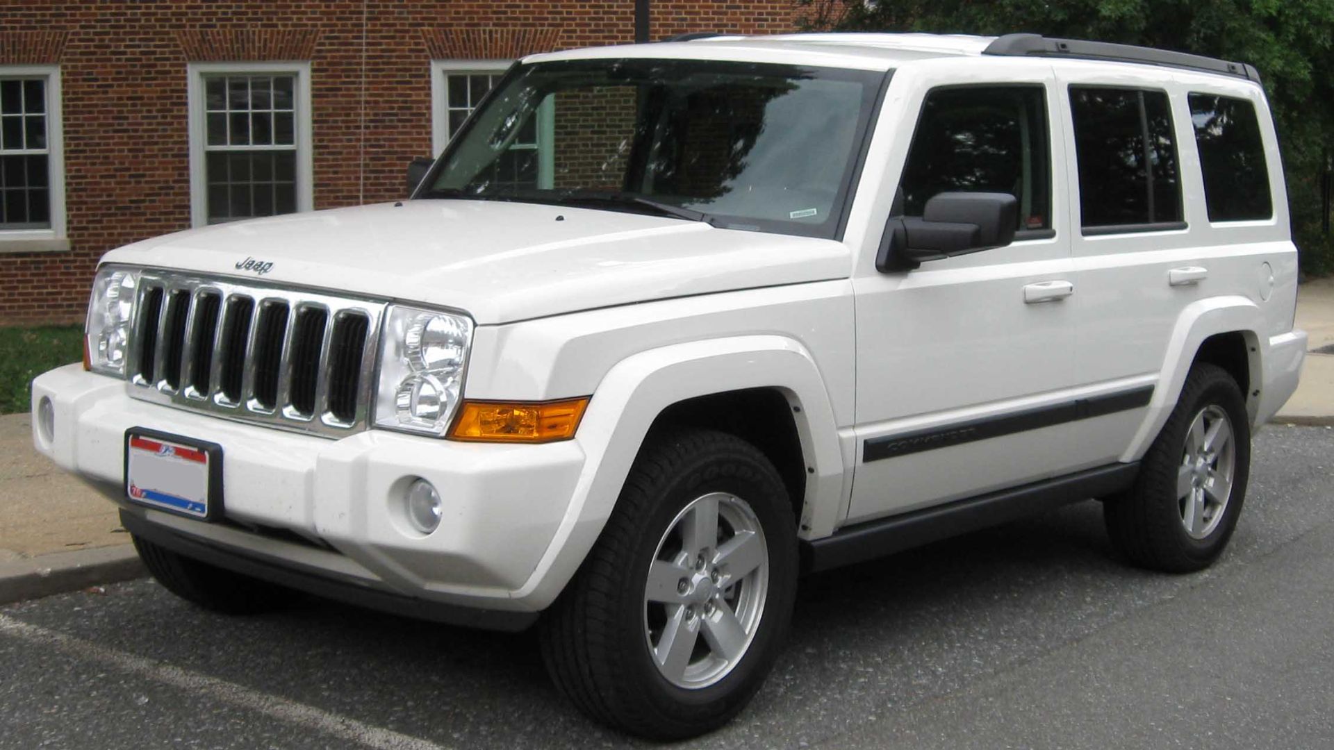 a white jeep parked in front of a brick building.