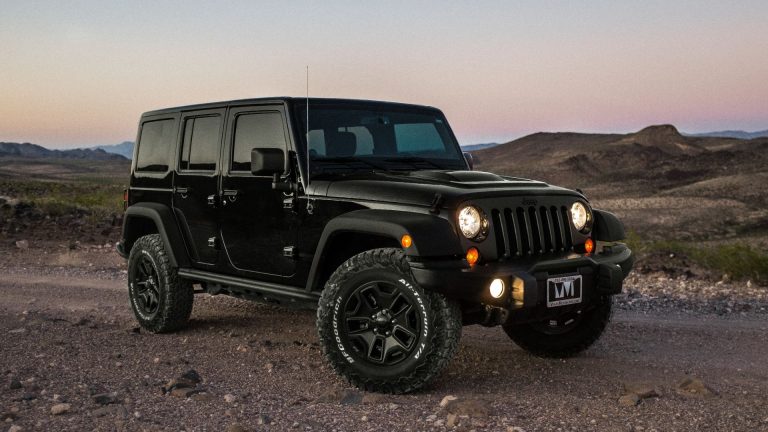 a black jeep is parked on a dirt road.
