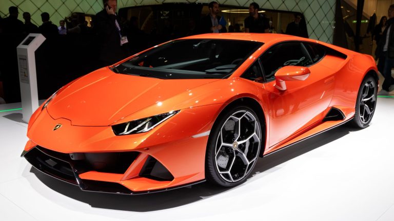 a bright orange sports car on display at a car show.