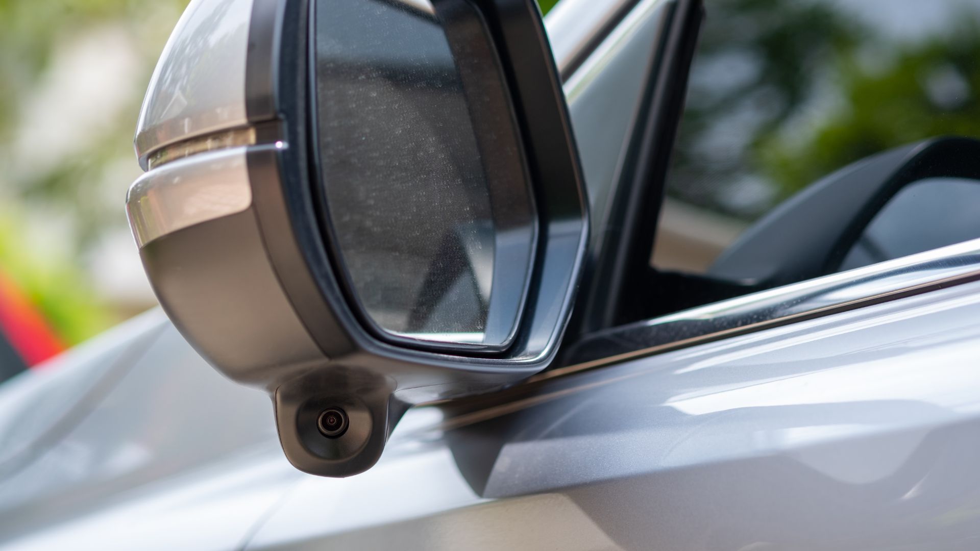 a close up of a car mirror with trees in the background.