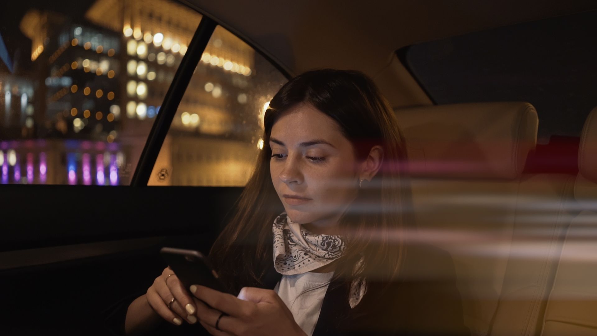 a woman sitting in a car looking at her cell phone.