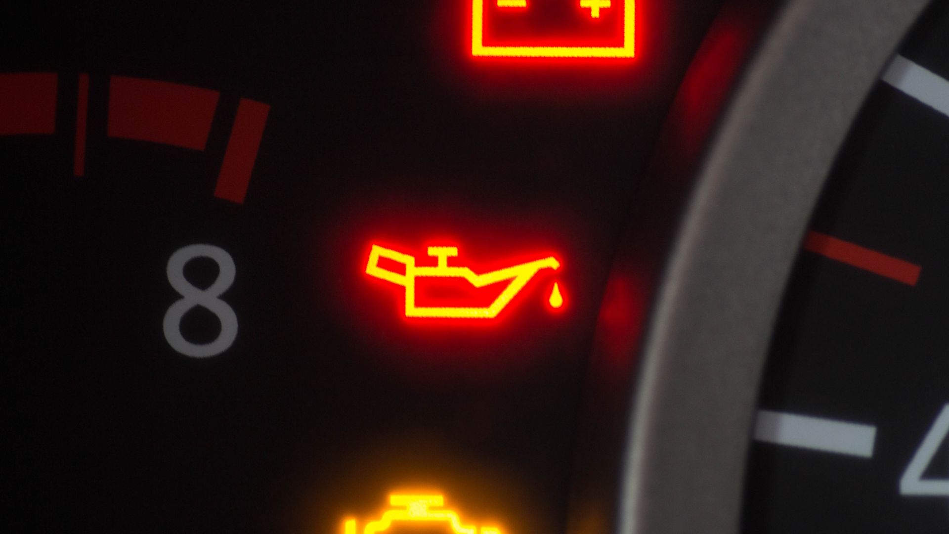 a close up of a speedometer with red and yellow lights.