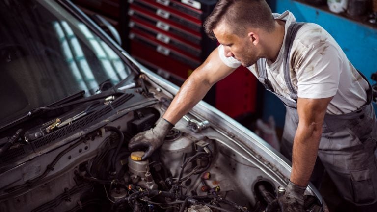 a man working on a car engine in a garage.