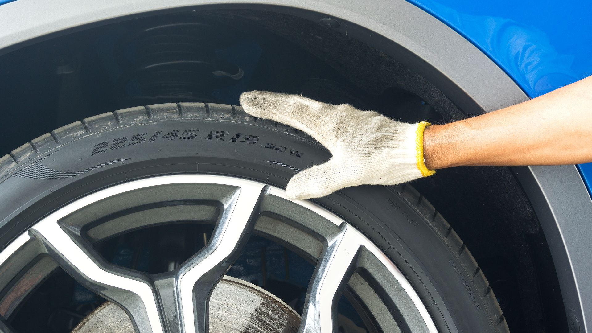 a person with a glove cleaning a car tire.