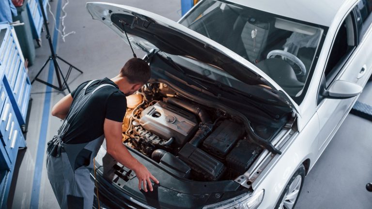 a man working on a car engine in a garage.