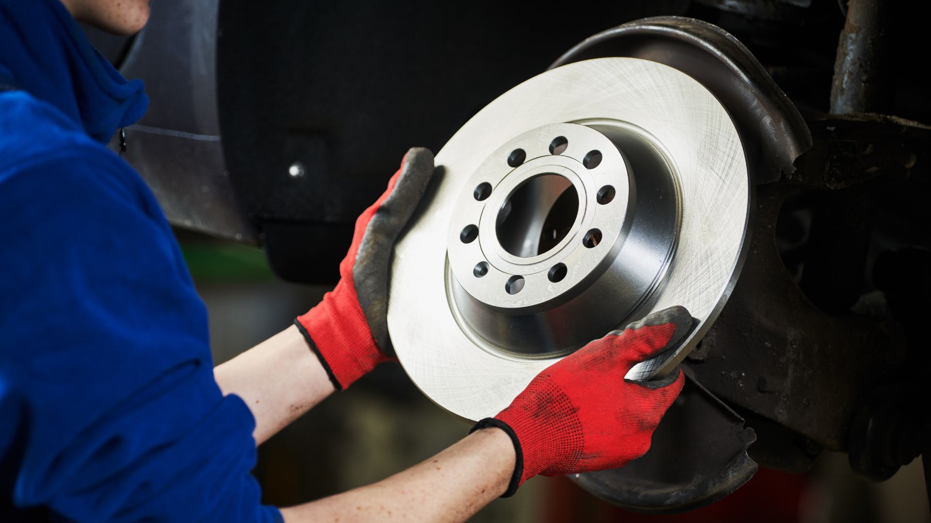 a woman is working on a brake assembly.