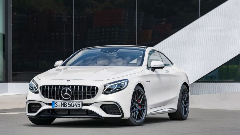 a white mercedes benz coupe parked in front of a building.