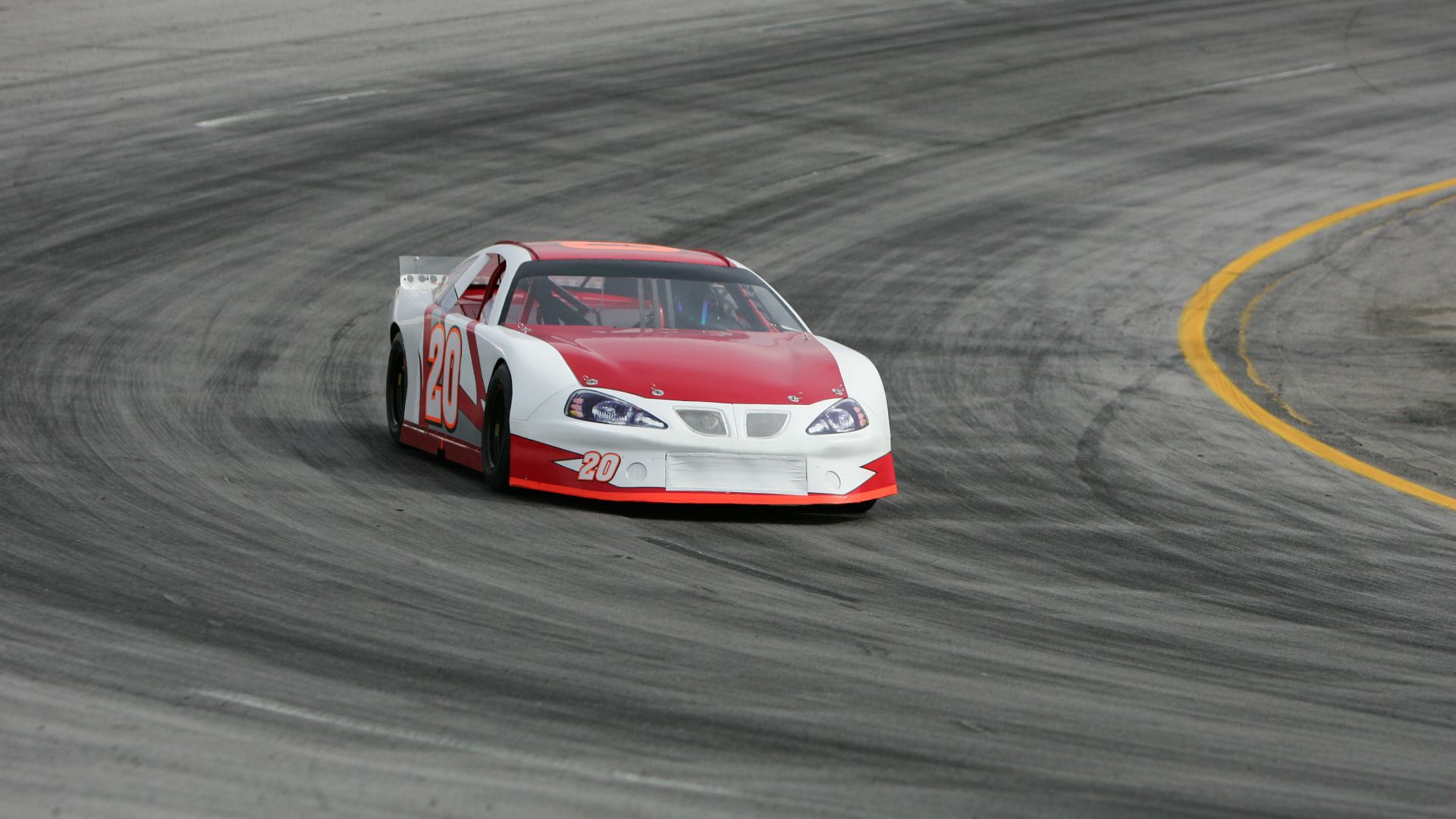 a red and white car driving on a race track.