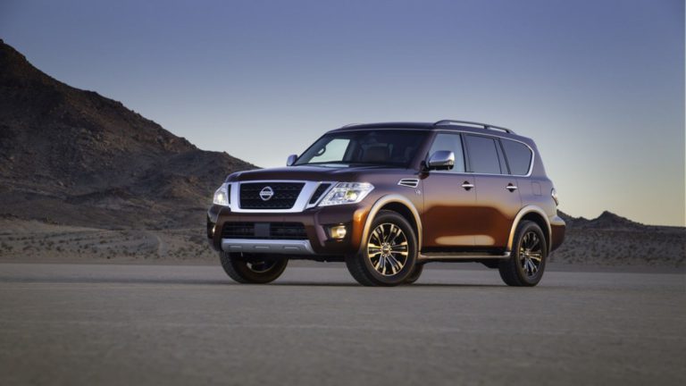 a brown nissan suv is parked in the desert.