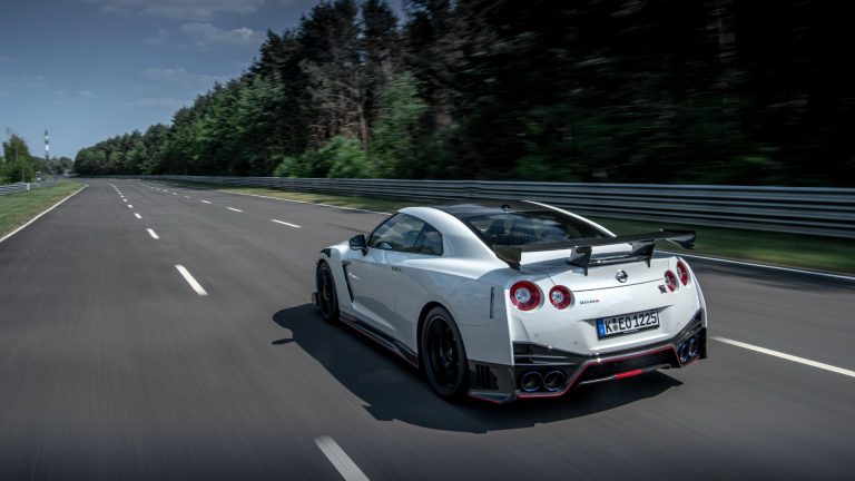 a white sports car driving down a road.