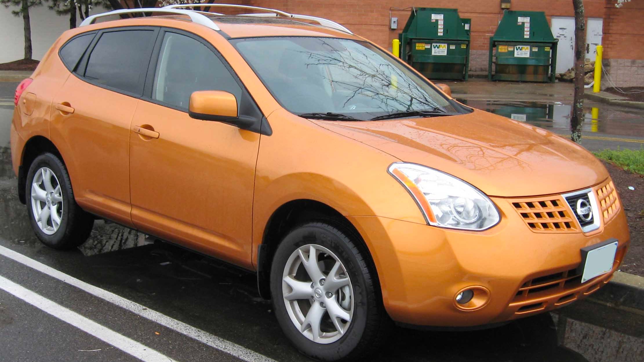 a small orange car parked on the side of the road.