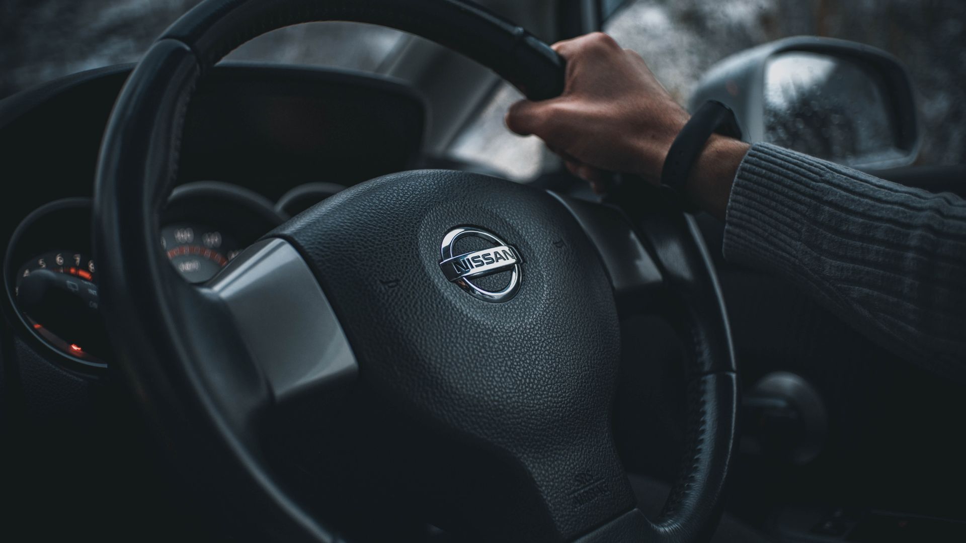 a person holding the steering wheel of a car.
