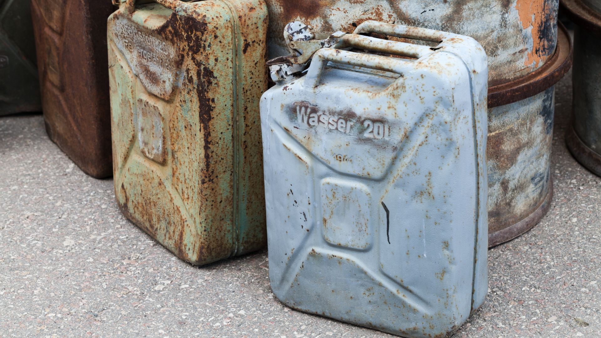 a group of rusty gas cans sitting next to each other.
