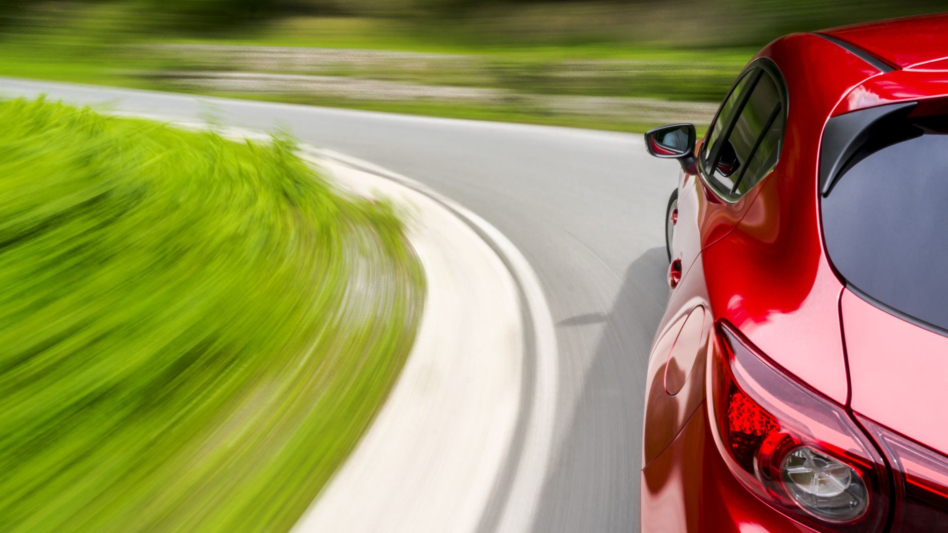 a red car driving down a curvy road.