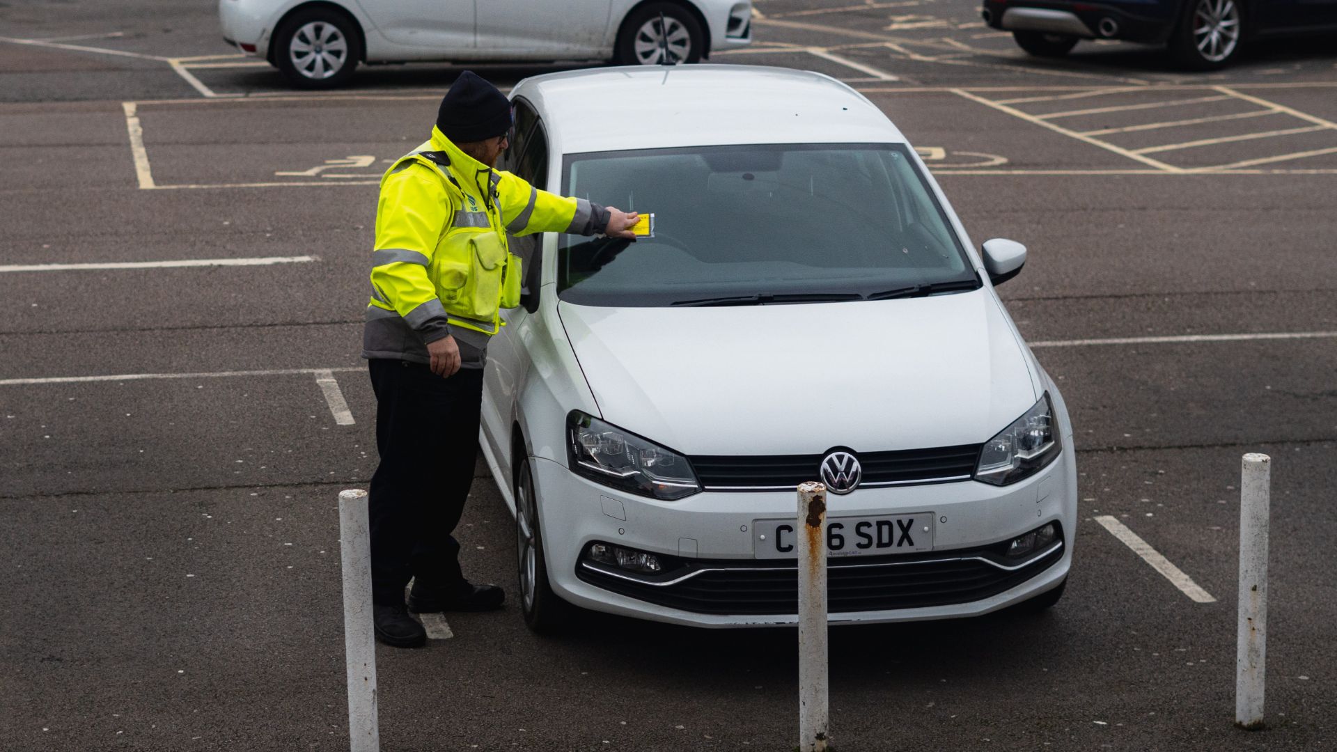 a man in yellow jacket next to a white car.