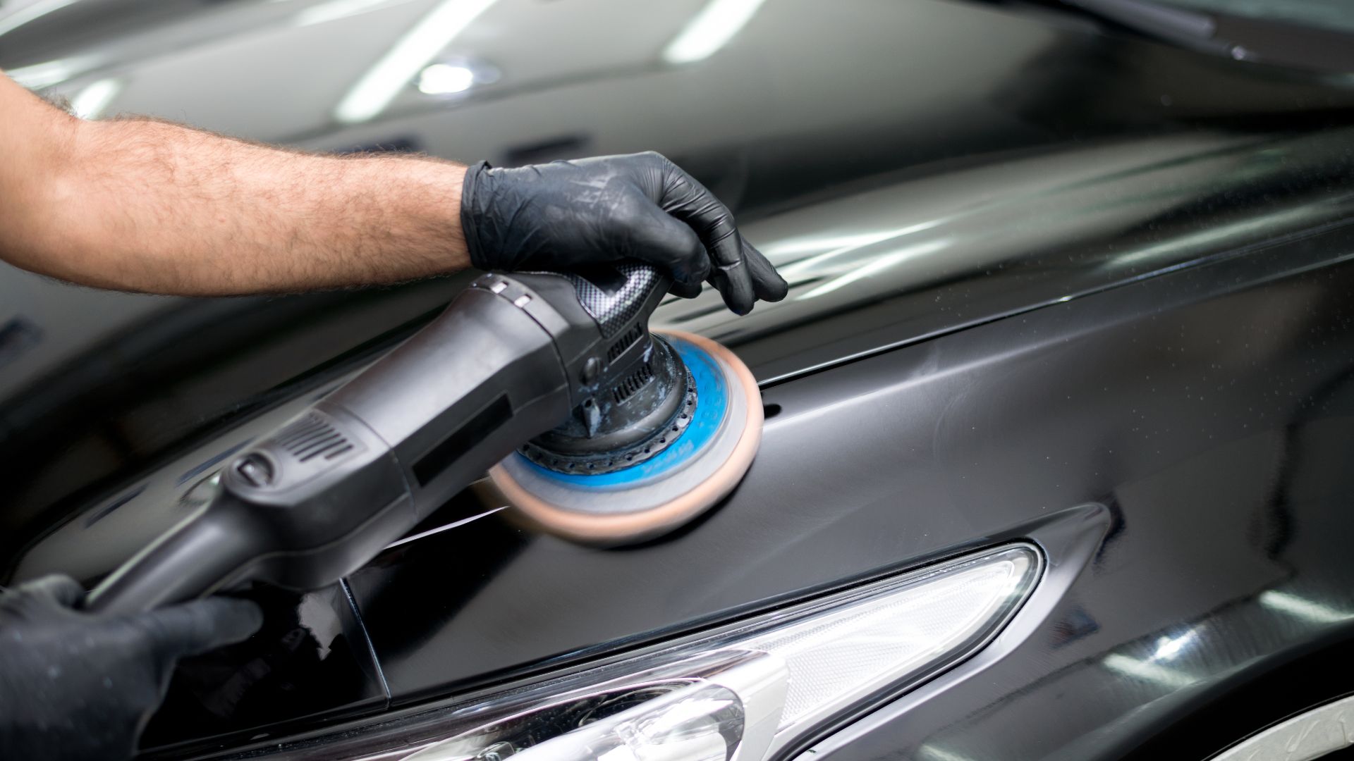 a man polishing a car with a polisher.