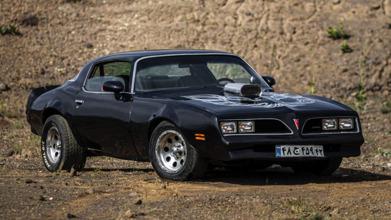 a black sports car parked on a dirt road.