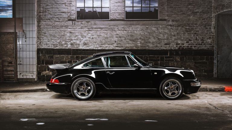 a black car parked in a garage next to a brick wall.