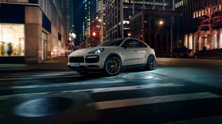 a white car driving down a city street at night.