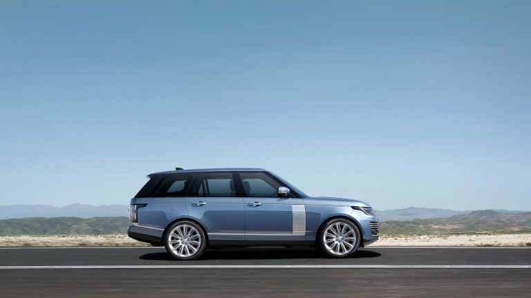 a blue range rover is driving down the road.