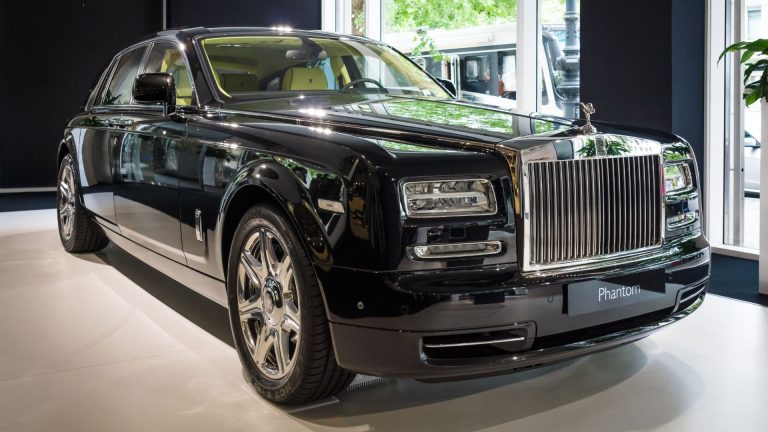 a black rolls royce parked in a showroom.