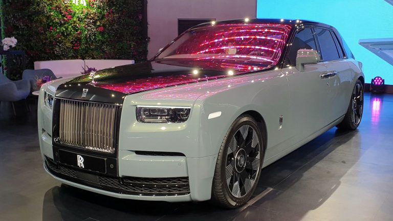 a white rolls royce parked in a showroom.