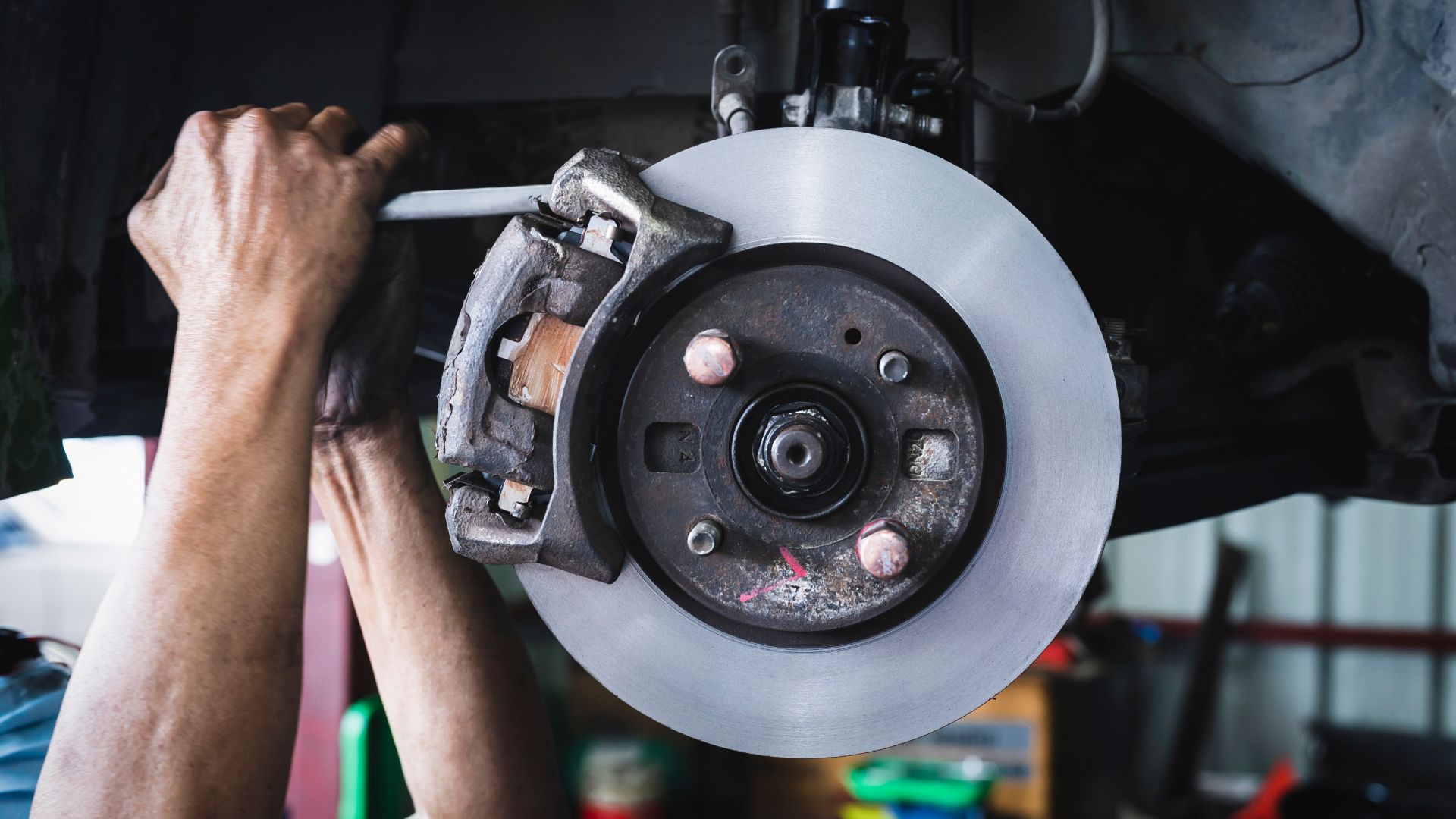 a man working on a brake assembly in a garage.