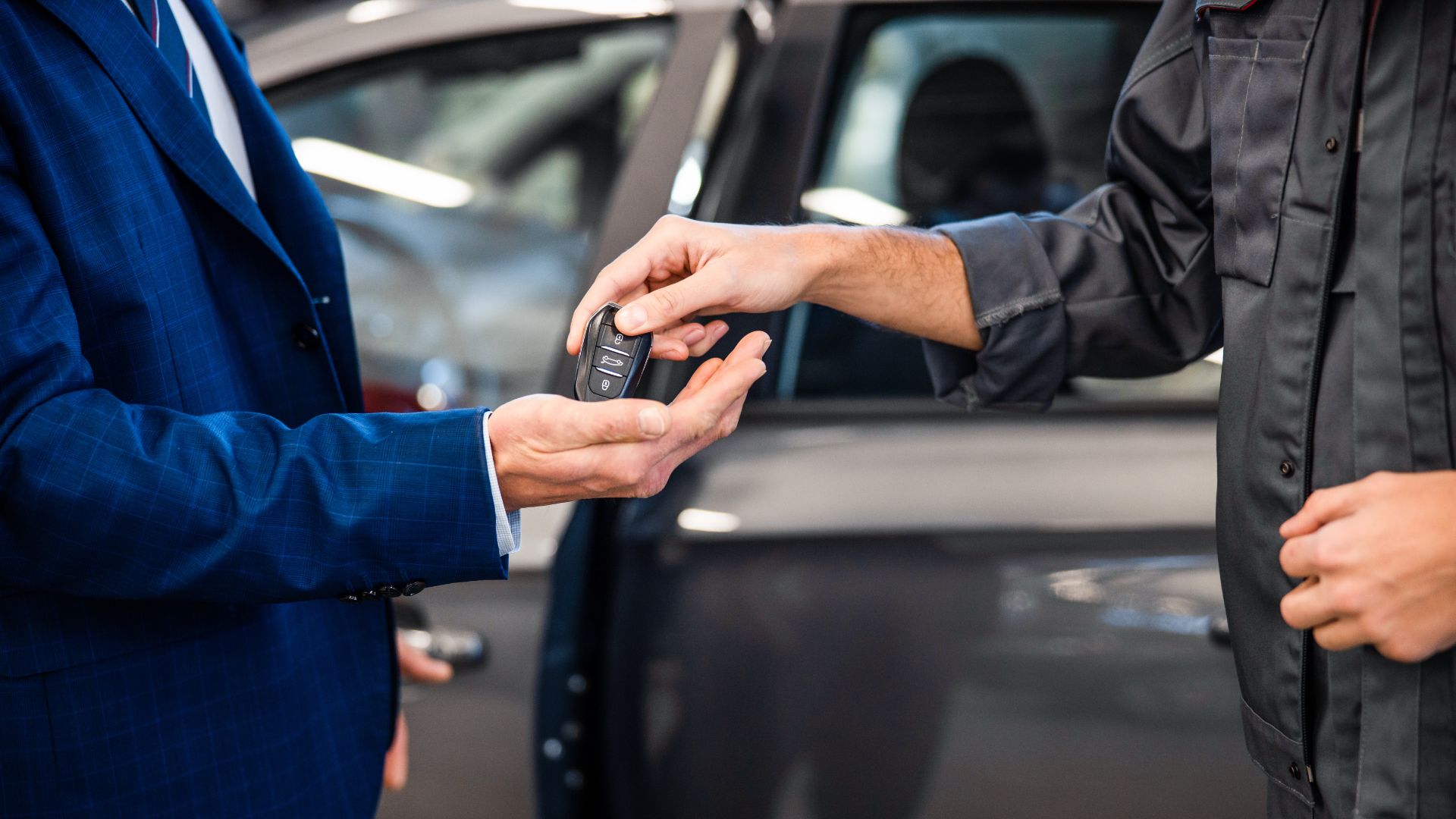 a man in a blue suit holding a car key.