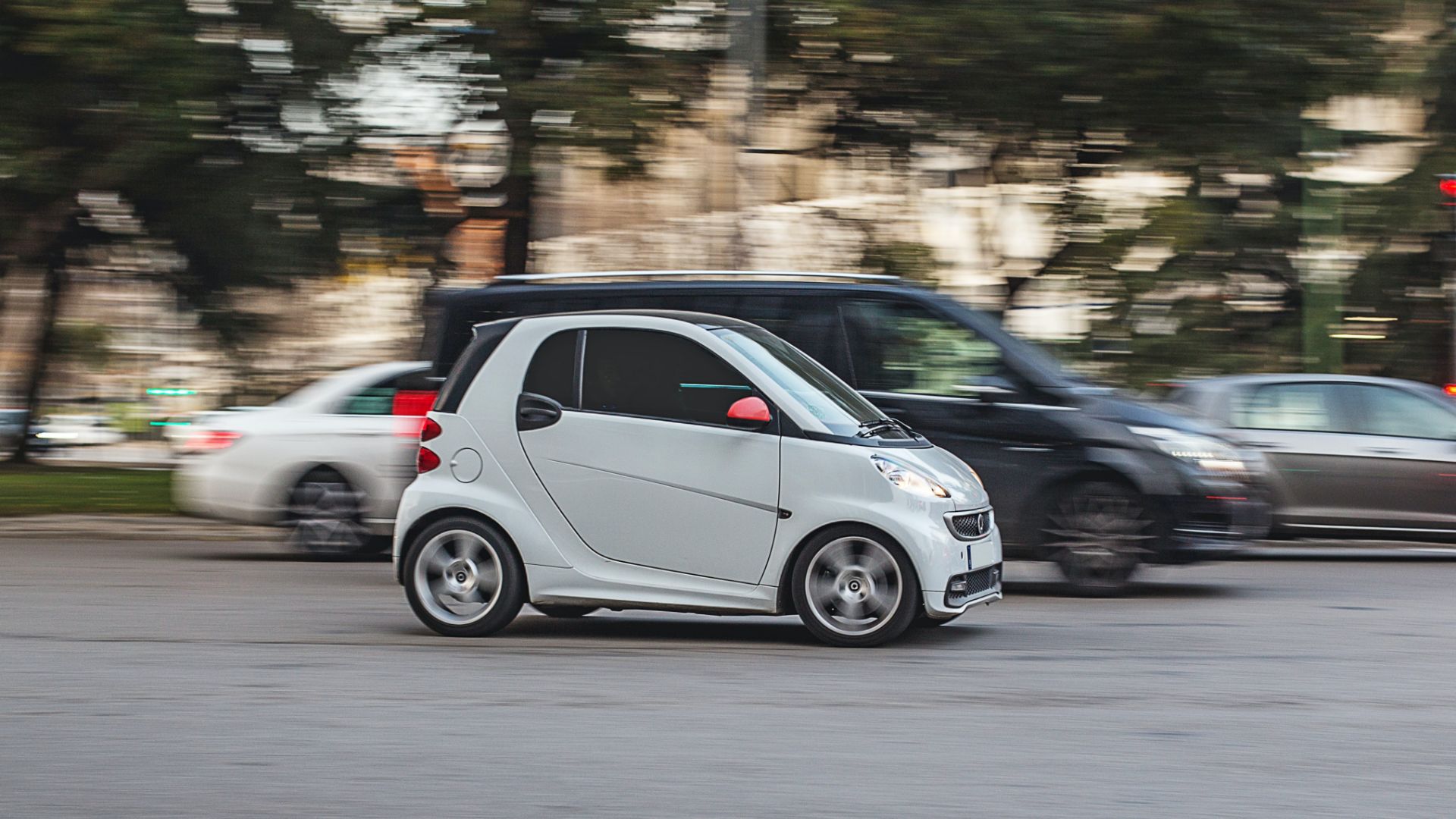 a smart car driving down a street next to other cars.