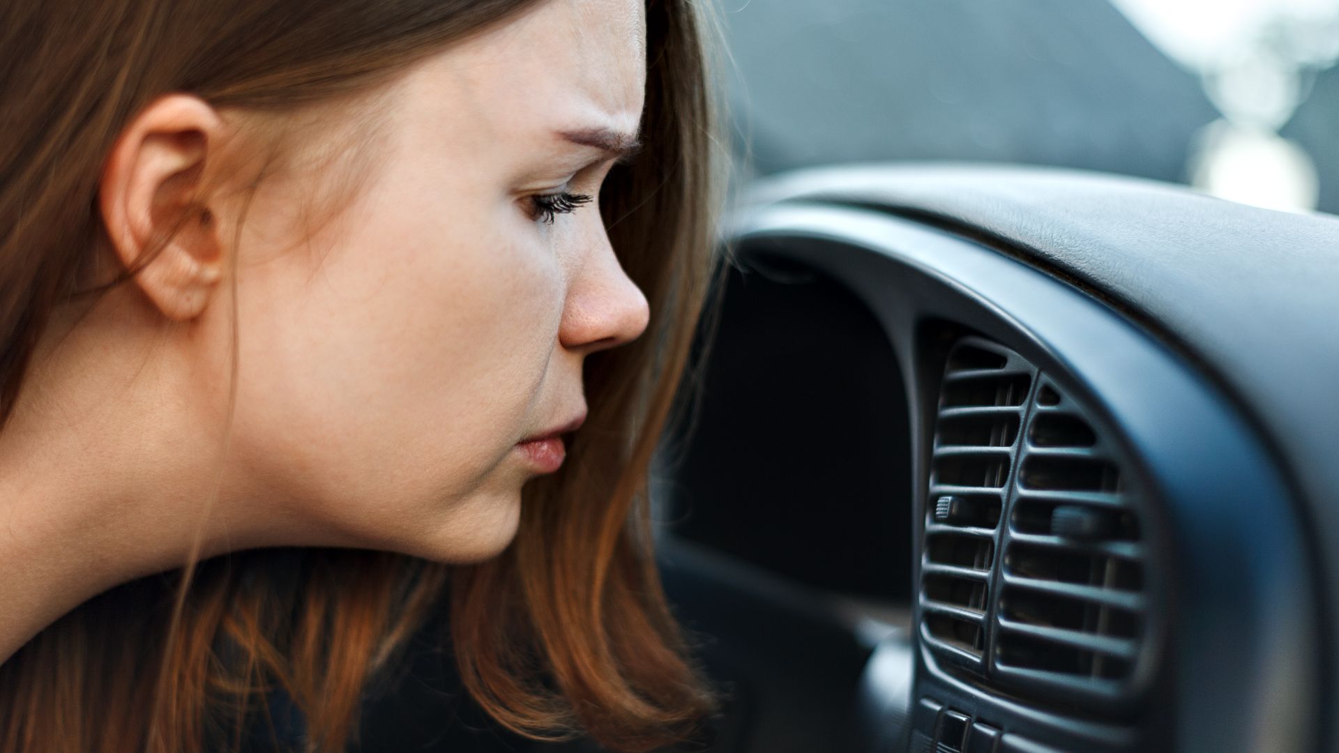 a woman looking at the air conditioner in her car.