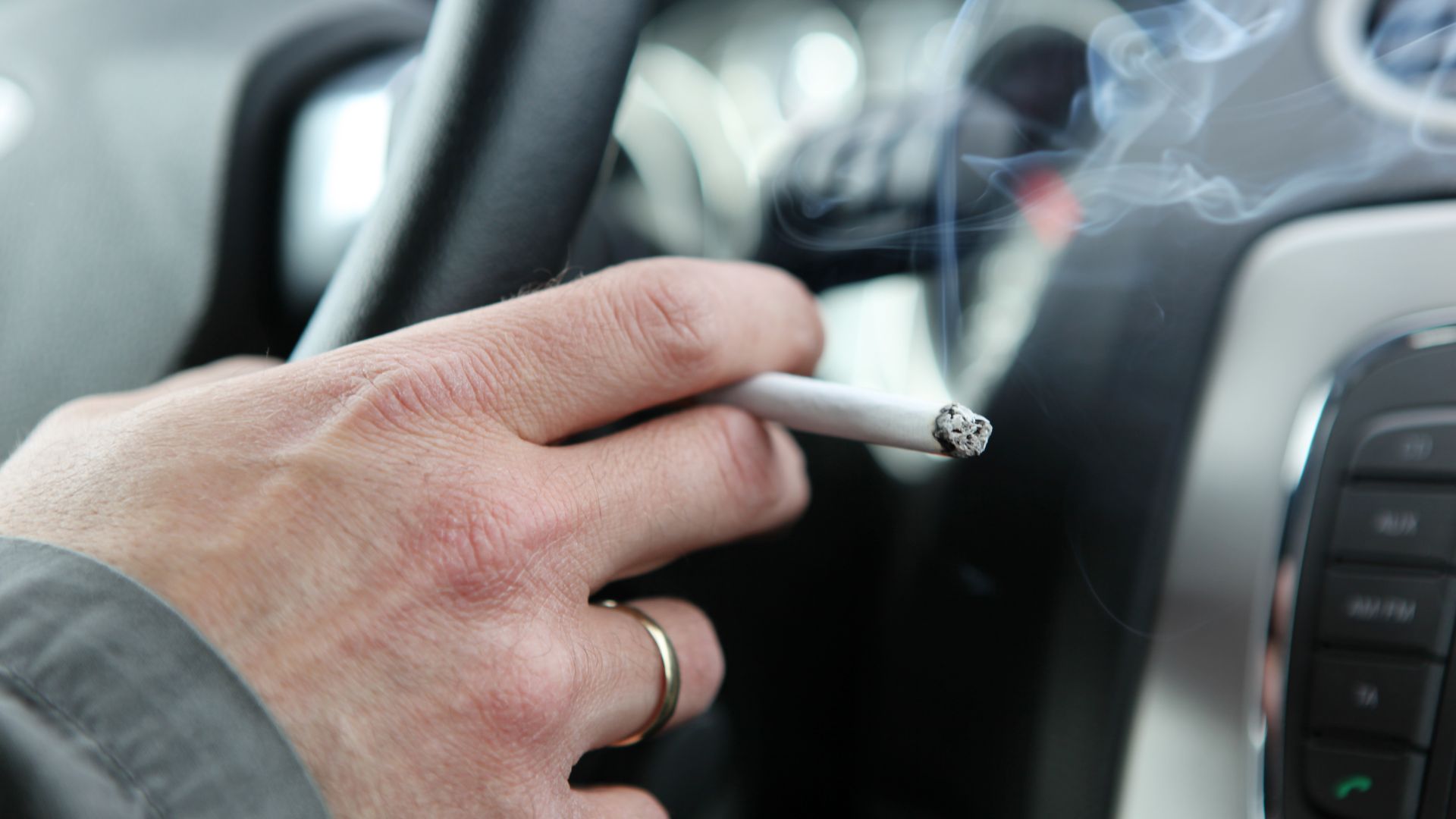 a person smoking a cigarette in a car.