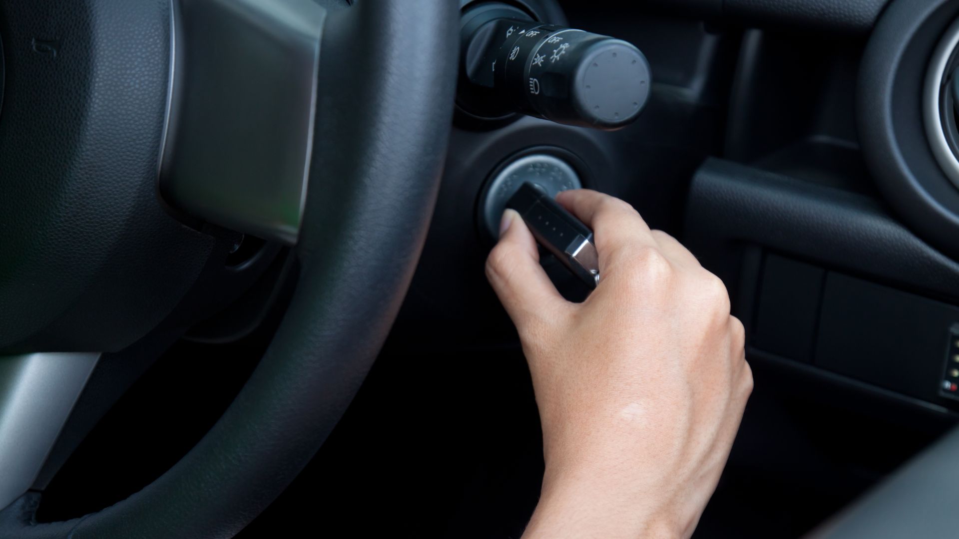 a person pressing a button on a car's steering wheel.
