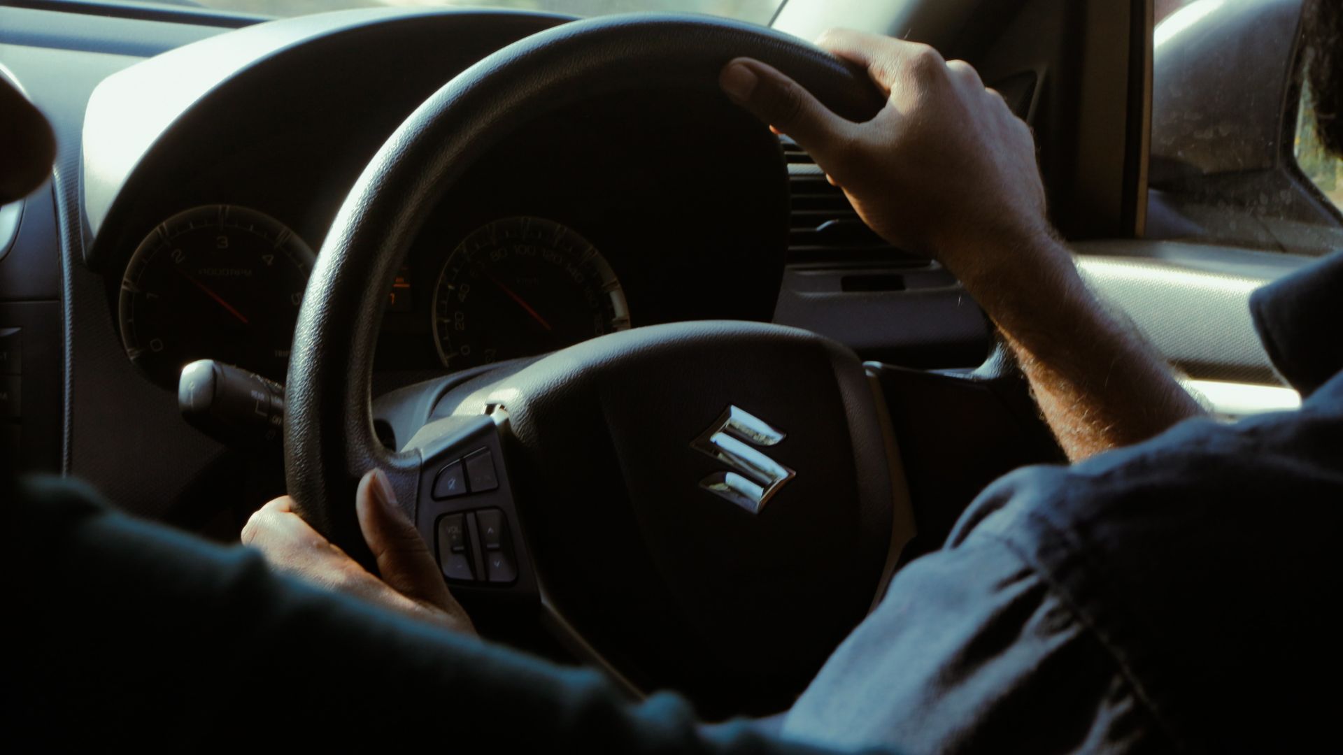 a man driving a car with a steering wheel.