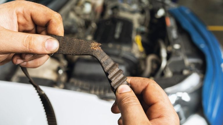 a man holding a wrench in front of a car engine.