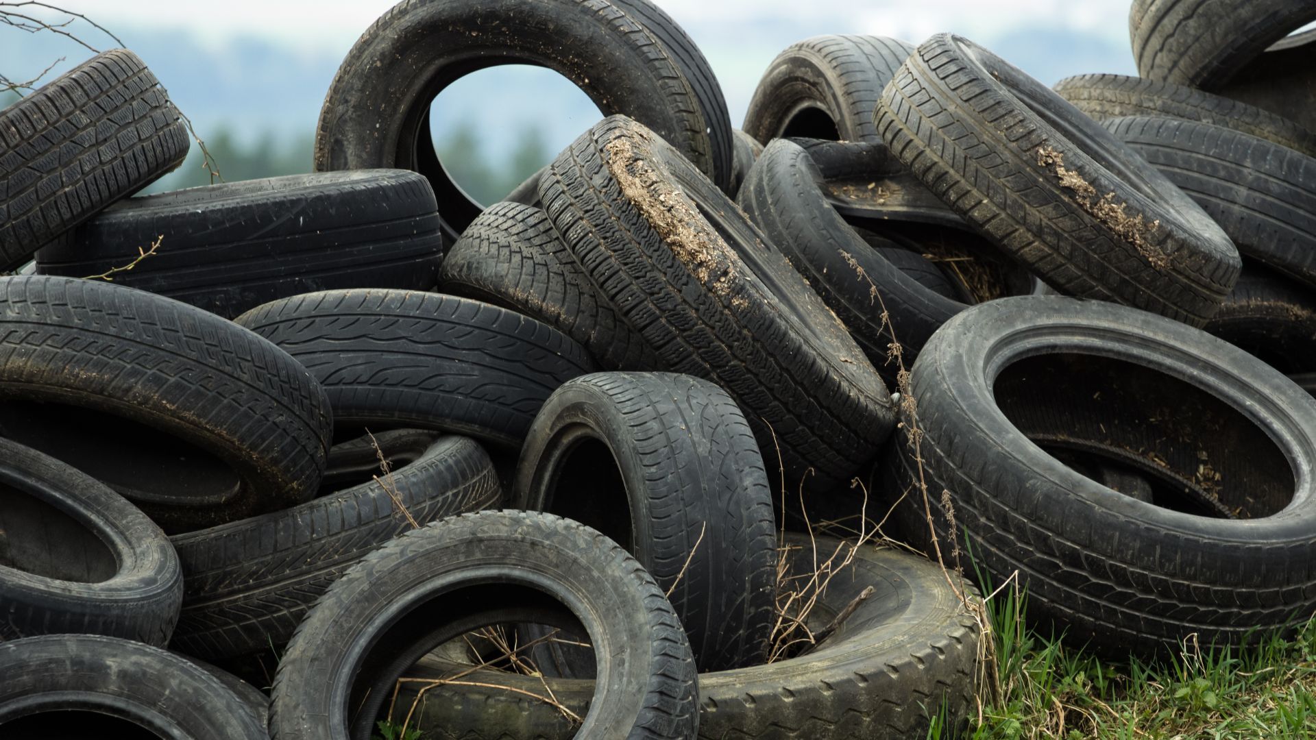 a pile of old tires sitting in the grass.